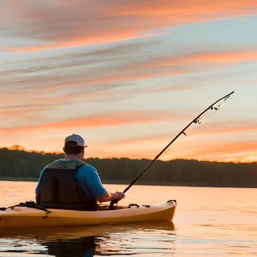 Man fishing in a kayak at sunset