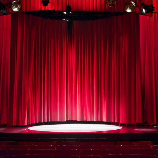 Stage with red curtains and a spotlight shining on the center.